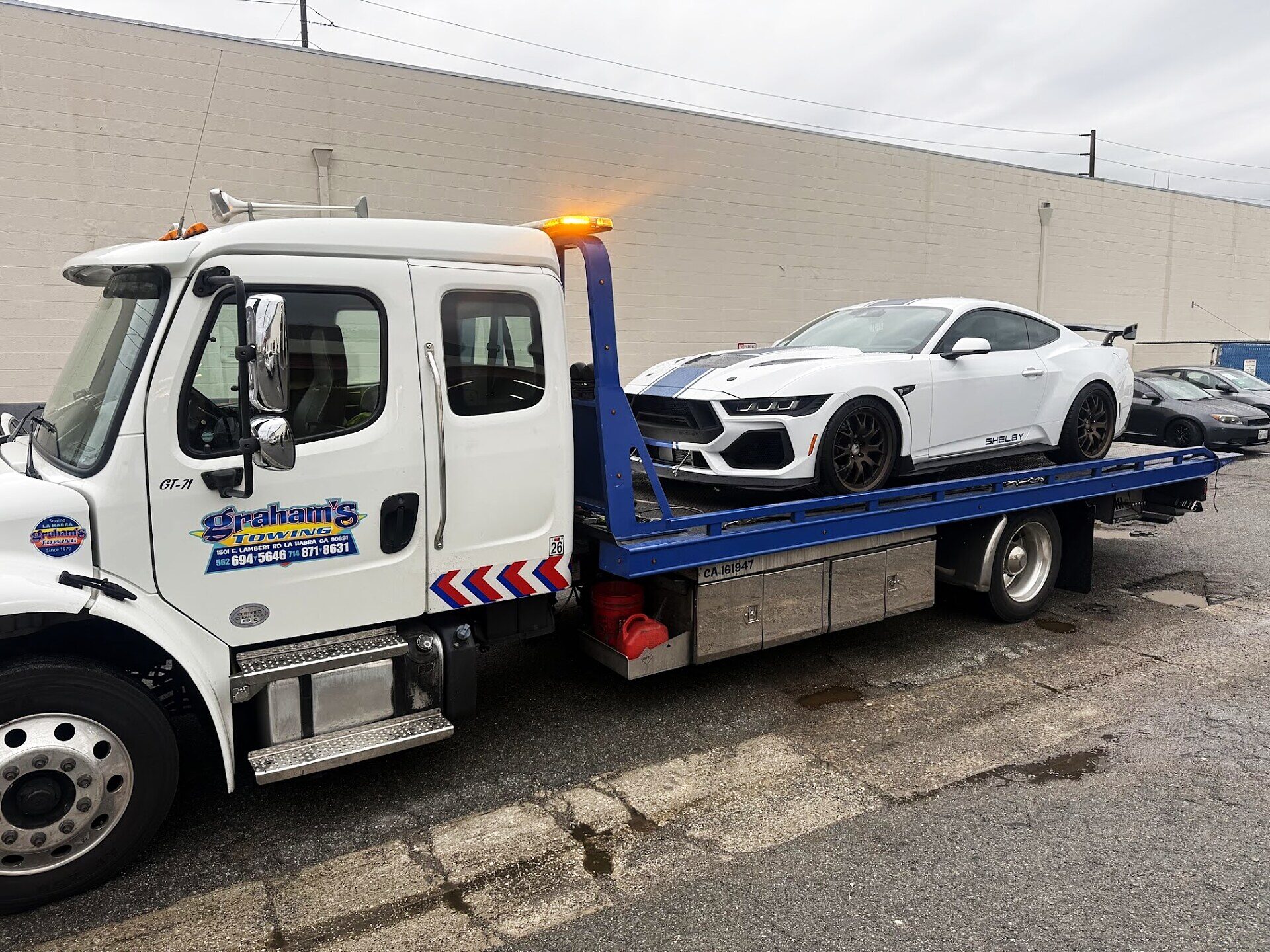 Graham's Towing flatbed truck loaded with a white Shelby Mustang in La Habra, CA